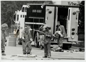 Hosed down: A firefighter from Richmond Hill's hazardous chemicals unit, is hosed down by a colleague today after leaving a Markham industrial plant after a nitric acid solution leaked