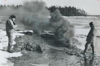 Making a test burn of oil slick along the south shore of Nova Scotia's Chedabucto Bay, workmen watch black smoke billow up from the thick seepage of bunker oil from [Incomplete]