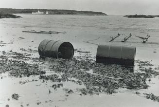 Two oil drums from the tanker Arrow come to rest on a polluted beach near Artichat, N