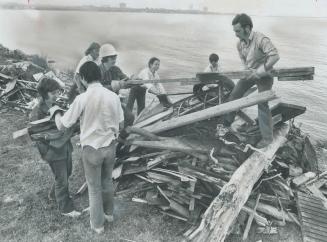 Cleaning up the lakefront between the Humber and Mimico Creek, Ed Wingate hands wood to Anne Ledingham, behind them, Mark Dodson atop pile receives bo(...)
