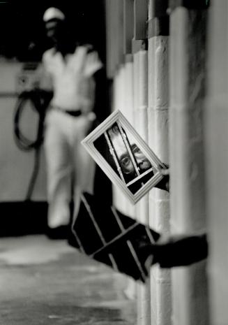 Bill Fuller, left, uses a mirror to get the view from outside his cell