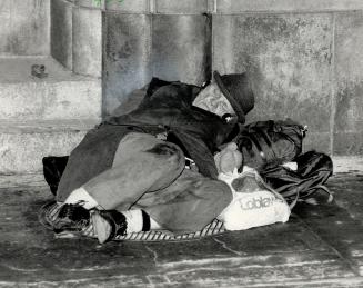 Bundled up against the cold of a January morning, one of Toronto's homeless tries to find some warmth early today sleeping on a ventilation grate outs(...)