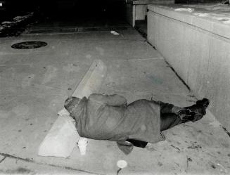 A homeless man uses a mitten atop a concrete barrier for a pillow as he sleeps in freezing temperatures in the Dundas St. W. Simcoe St. area last nigh(...)