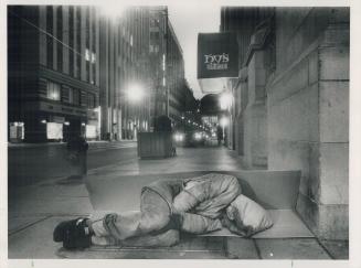 A sheet of cardboard is a bed for a homeless youth on a downtown Toronto street