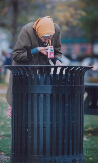 Grim times: An elderly woman finds something to eat and drink in a garbage can on York Quay