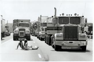 Taking advantage: Two sunbathers make the best of a no-way-out situation yesterday on Highway 401 as truckers refuse to budge