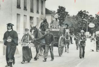 Two young men wearing papier-mache masks of Premier William Davis (left) and Prime Minister Pierre Trudeau are driven in a horse-drawn cart through th(...)