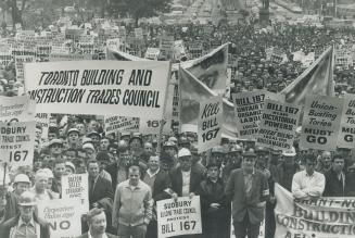 Construction workers holding banners and placards stand in front of Queen's Park yesterday in a massive demonstration to protest government's proposed amendments to Labor Relations Act