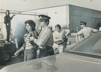 In picket line skirmish outside an auto parts plant in Etobicoke yesterday, a police constable leads away Lorrie Cecelia Atlee, 18, of Hamilton, while(...)