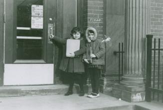 Two children stand in front of library entrance.