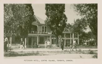 Picture of two storey clapboard hotel with large verandahs and people walking past on the sidew…