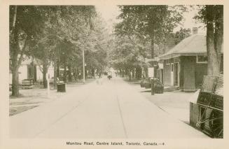 Photo of tree lined main street with shops on either side of the wide pavement. 