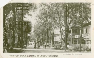 Photo of tree lined main street with shops on either side and large hydro poles on left side of ...