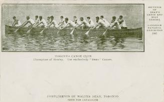 Black and white picture of fifteen canoeists paddling in a large canoe.