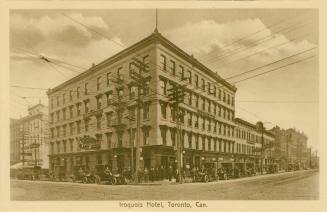 Sepia toned photograph of a five story hotel building on a street corner.