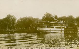 Shows a picture of a ferry steam ship docked on Toronto Island.