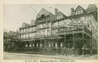 Black and white picture of a large hotel building with signs, &quot;K of C Catholic Army Huts E ...