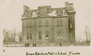 Black and white photograph of a three story, Victorian school building in the wintertime.