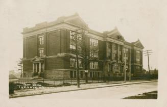 Black and white photograph of a three story school with columns over the front door.