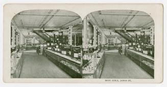 Pictures show glass cases on either side of an aisle in a large store.