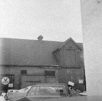 A photograph of a barn with a car in front of it.