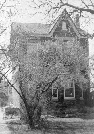 A photograph of a house with a tree in front of it.