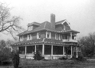 A photograph of a house with a porch and a second floor balcony.