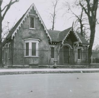 A photograph of a house with a fence in front of it.