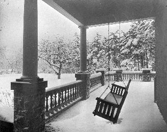 A photograph of the front porch of a house during winter.