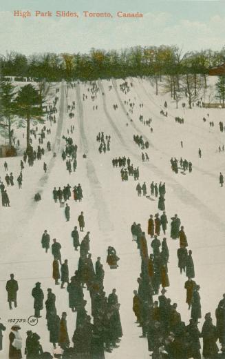  Crowd of people sliding down six individual snow slides. 