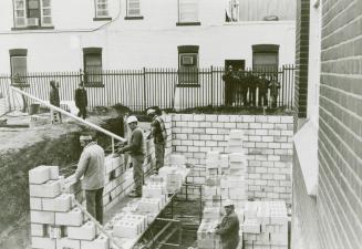 Four men building brick basement walls at Main Street library
