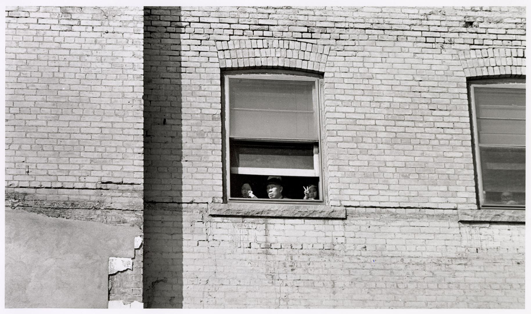 A photograph of a man looking out of a window.