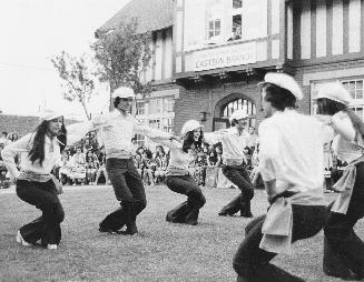 Greek dancers on a lawn linking arms