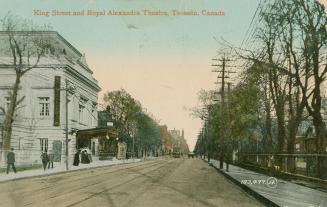 Color picture of a city street with a theater on the left hand side.