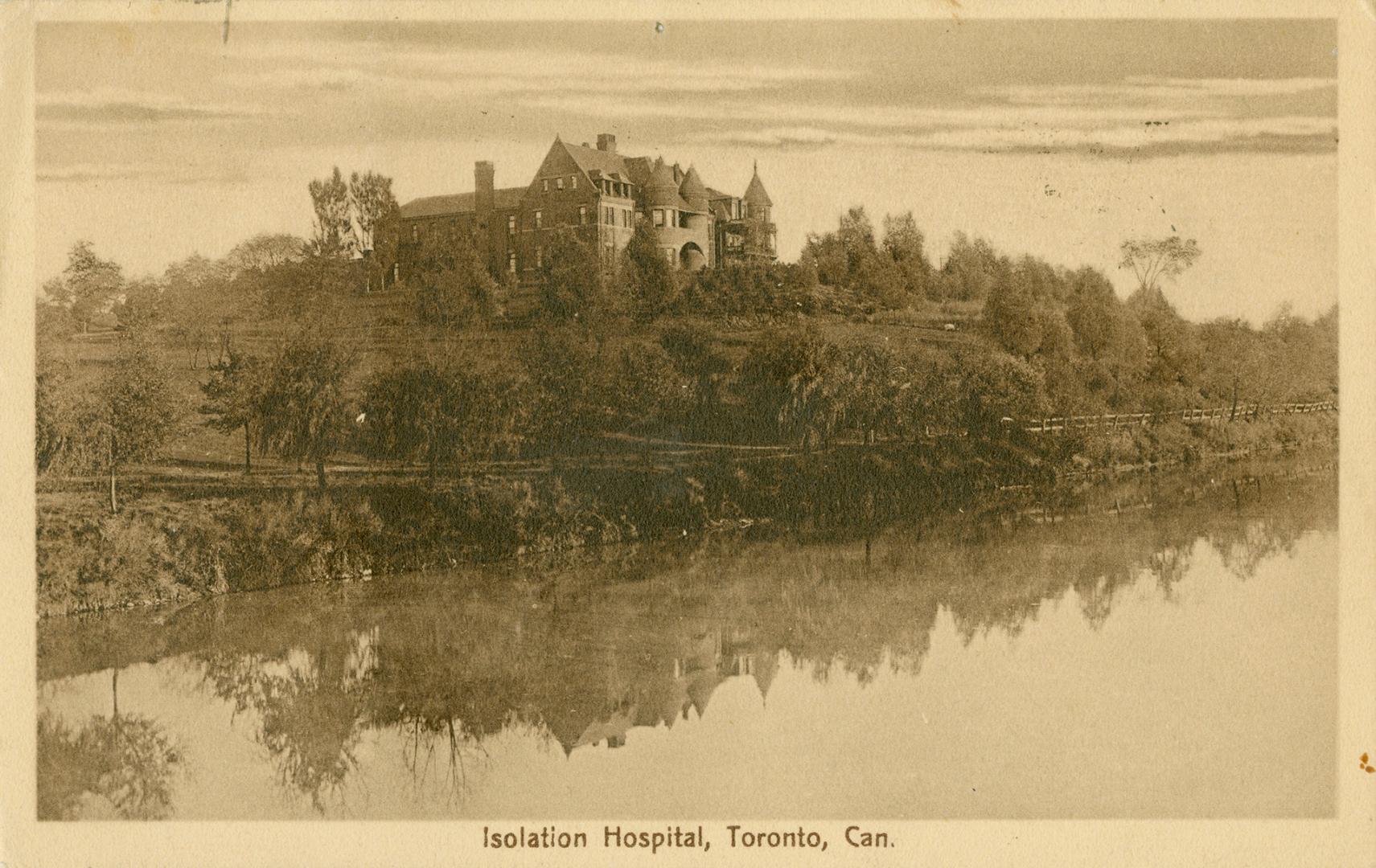 Sepia toned picture of a large hospital complex, taken from below in the a valley with a river.