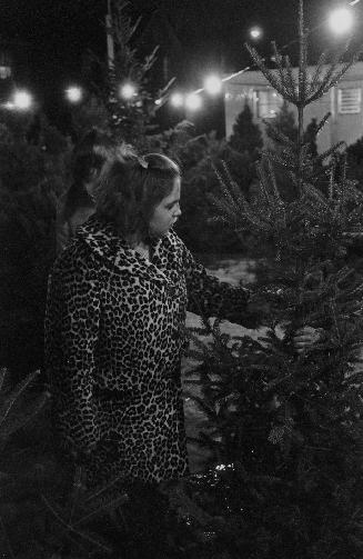 A photograph of a woman holding a Christmas tree.