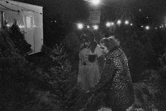 A photograph of two women looking at Christmas trees.