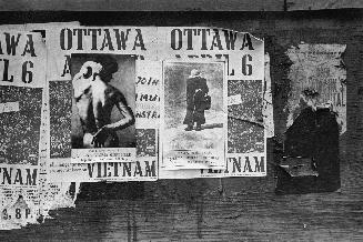 A photograph of torn posters plastered on a wall.