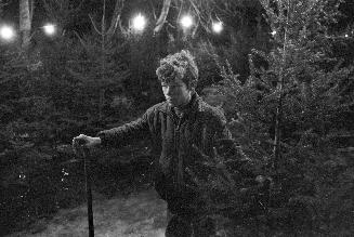 A photograph of a young man holding a Christmas tree.