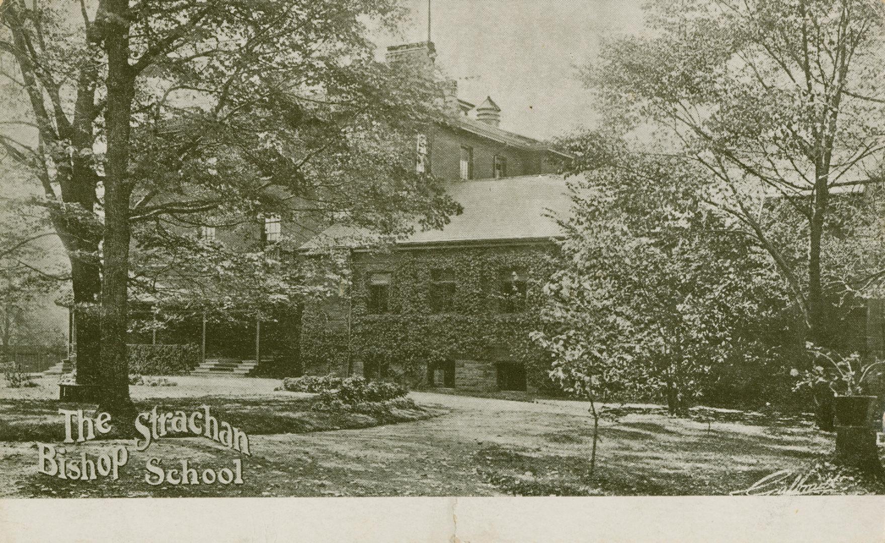 Black and white photograph of a large home with another building covered in ivy beside it.