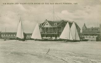 Black and white picture of ice boats on a lake n front a of large building.