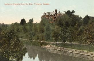 A turreted multi-story red brick building partially hidden by trees, on a hill a few feet from …