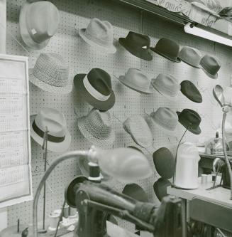 A photograph of various hats displayed on a wall above sewing machines.