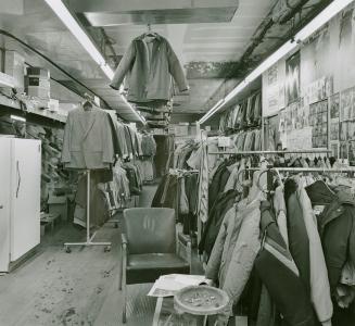 A photograph of a clothing store, with hanging racks of clothing including coats and jackets vi ...