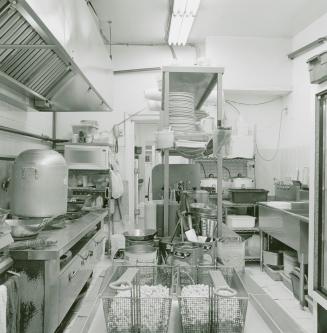 A photograph of a restaurant kitchen, with a stove, oven, deep fryer and dishwashing equipment  ...