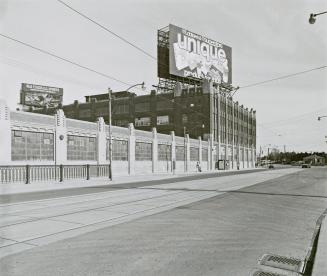 A photograph of a building on the left side of a road. Above the building is a Loblaws billboar ...