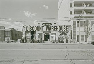 A photograph of a store named Rotblott's Discount Warehouse, with a street in the foreground an…