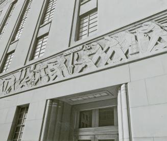 A photograph of a frieze above a doorway, depicting workers in various industries and professio…