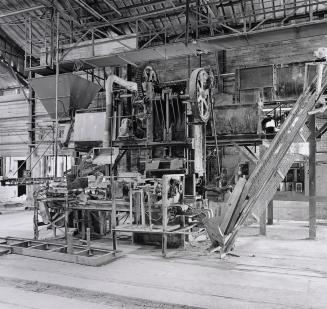 A photograph of a mud-pressing machine inside a brick works factory.