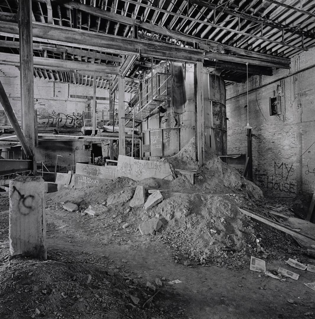 A photograph of a water tank inside a factory building, surrounded by rubble.
